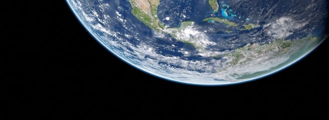 A view of Earth from space, highlighting the North American continent, including the western coast of the United States, parts of Mexico, and Canada. The Earth appears with a mix of land, water, and cloud formations against the blackness of space.