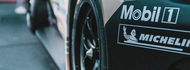 A close-up view of the rear section of a race car, focusing on the rear tire and part of the car's body.